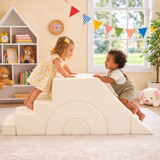 Two children playing on a soft play structure in a room with toys and books.