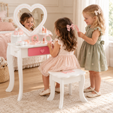 Two girls playing dress-up at a children’s heart mirror vanity table with pretend salon accessories