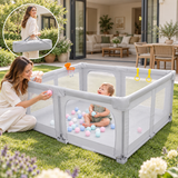 Baby enjoying supervised outdoors play inside a grey mesh playpen with foam mat