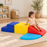 Toddler sitting on the red foam slide beside the yellow soft play platform
