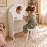 Three-year-old girl drawing at a white dressing table with matching round stool