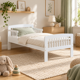 White solid pine toddler bed with side rails and cream bedding in a neutral children’s bedroom