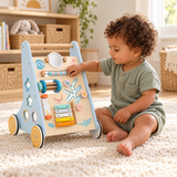 Toddler seated beside the ocean activity walker exploring its bead bar.