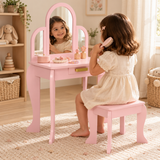 Three-year-old girl brushing her hair at a pink dressing table in a neutral playroom