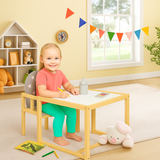 Child sitting at a small wooden table and chair set in a colourful playroom with toys 
