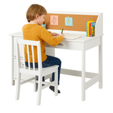 Child sitting at a white wooden study desk with a corkboard and book