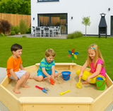 Large octagonal sandpit in a garden with children playing