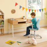 Child sitting at a homework desk in a playroom with toys and decorations.