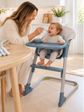 Mum feeding 10 month old baby in blue/grey highchair in modern white kitchen