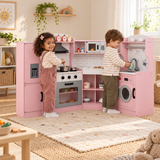 Two children playing with a pink wooden corner kitchen with sound and light features in a neutral playroom.