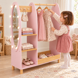 Three-year-old girl choosing a dress from a pink wooden clothes rail with light-up mirror.