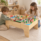 Two children enjoying the wooden train table together on a cream playroom rug.