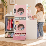 Girl using the pretend sink on a pink wooden laundry playset with opening washing machine doors and storage
