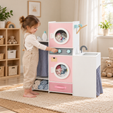 1. Child turning the washing machine dial on a pink wooden laundry playset with pretend sink and clothes storage