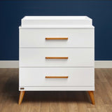 La commode avec meuble à langer Melody présente un style extrêmement moderne, avec un mélange de finitions blanc et bois.