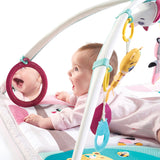 Un gran espejo cuelga de un arco para que el bebé pueda verse a sí mismo: otro elemento de desarrollo en esta alfombra de juego multisensorial para bebés.